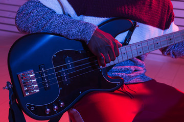 Create music and a recording studio concept - african american man guitarist recording electric bass guitar track in home studio, close-up.