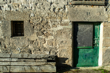 Muro de piedra con puertas y ventanas antiguas.