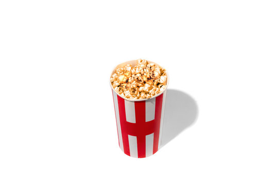Striped white red bucket full of popcorn isolated on white studio background with copyspace for advertising. Entertainment, food, traditional snacks, time for cinema and having fun, tasty.