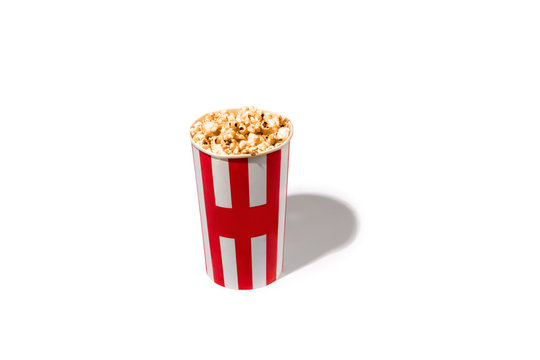 Striped white red bucket full of popcorn isolated on white studio background with copyspace for advertising. Entertainment, food, traditional snacks, time for cinema and having fun, tasty.