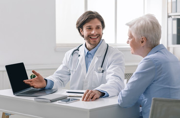 Geriatrician explaining test results to senior patient on laptop