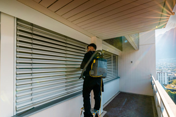 professional cleaner vacuum cleaning window blinds on an apartment balcony in a high-rise building