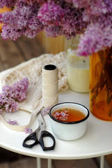 Obraz na płótnie Canvas Lilac, fresh tea and a seamstress set