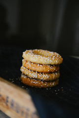 The sesame rolls are stacked on top of each other on a wooden tray. Dark background.