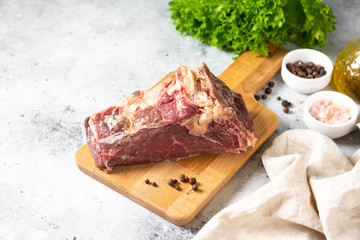 Raw beef meat on a wooden Board on the light gray kitchen table. Fresh piece of beef meat