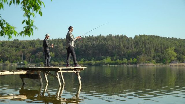 Two men are fishing on the lake. Spinning fishing predatory fish. Fisherman cast fishing rod in lake or river water