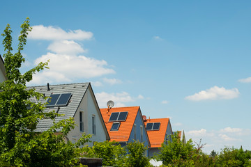 House roofs with solar panels in a residential area in sunshine. Sustainable energy. 