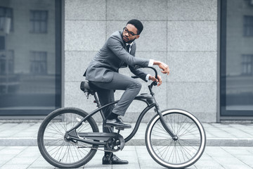 Handsome afro businessman riding his bike to work - Powered by Adobe