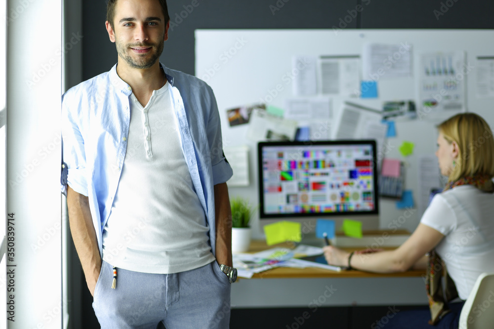 Poster portrait of young designer in front of laptop and computer while working. assistant using her mobile