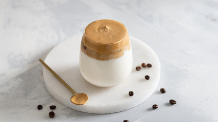 Homemade Dalgona coffee in glass with coffee beans on white table. Recipe popular Korean drink latte with foam of instant coffee. Created new drink during Quarantine and self-isolation.