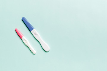 Colored Pregnancy test on colored background, top view with copy space