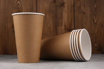 Six eco-friendly cups lie on a wooden background. The concept of ecology. Mock-up. Close-up.