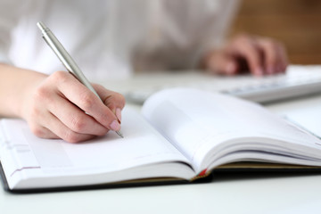 Female hand holding silver pen ready to make note