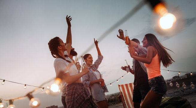Carefree group of happy friends enjoying party on rooftop terrace