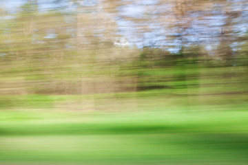 Defocused background of window view of moving car. Blurry image of grass, sky and trees