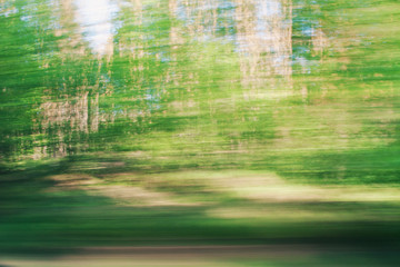 Defocused background of window view of moving car. Blurry image of grass, sky and trees