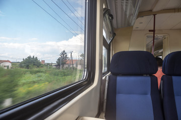 Empty seats in a modern regional train, European style, on a travel in a countryside with a speed blur effect seen from the window