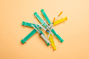 Top view of a heap of syringes and insulin syringes at orange background. Medical injection concept with copy space