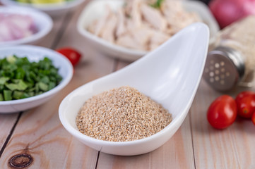 Roasted rice in a white spoon, tomato placed on a wooden table.