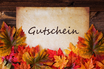 Grungy Old Paper With German Text Gutschein Means Voucher. Colorful Autum Decoration With Leaves