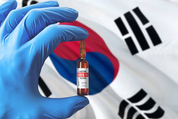 South Korea flag with Coronavirus Covid-19 concept. Doctor with blue protection medical gloves holding a vaccine bottle. Epidemic Virus, Cov-19, Corona virus outbreaking.