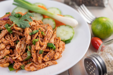Spicy minced chicken on a white plate complete with cucumber, lettuce and side dishes.