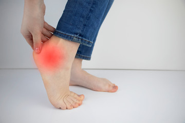 Woman suffering from heel pain. Inflammation or sprain of the tendon in the foot, heel spur,...