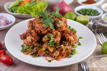 Spicy minced chicken on a white plate complete with cucumber, lettuce and side dishes.