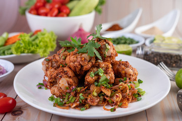 Spicy minced chicken on a white plate complete with cucumber, lettuce and side dishes.