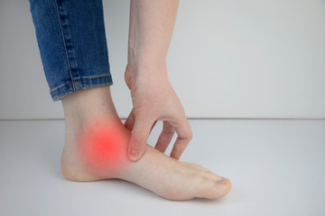 Woman suffering from heel pain. Inflammation or sprain of the tendon in the foot, heel spur,...