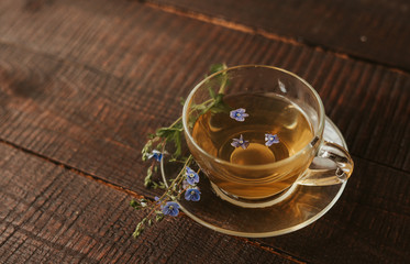 glass cup of tea with herbs. flowers in the cup.