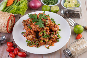 Spicy minced chicken on a white plate complete with cucumber, lettuce and side dishes.