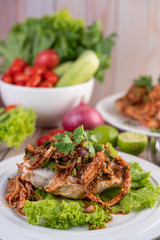Spicy minced chicken on a white plate complete with cucumber, lettuce and side dishes.