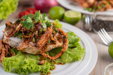 Spicy minced chicken on a white plate complete with cucumber, lettuce and side dishes.