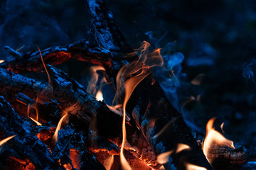 Night fire with a small flame, blue coals and smoke