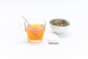 cup of green tea together with a bag and a bowl of crushed tea