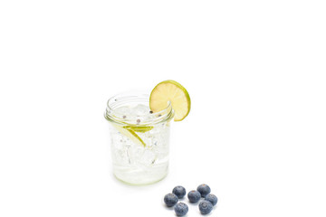 tonic jar with ice and a slice of lemon with some fruits on a white background