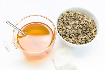 cup of green tea together with a bag and a bowl of crushed tea