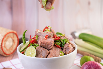Boiled pork ribs in a white cup on a piece of fabric on a wooden table.