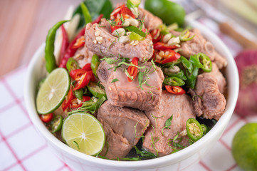 Boiled pork ribs in a white cup on a piece of fabric on a wooden table.