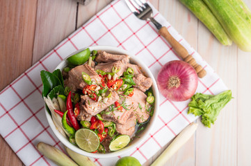Boiled pork ribs in a white cup on a piece of fabric on a wooden table.