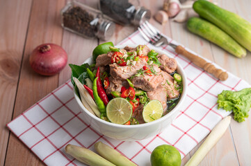 Boiled pork ribs in a white cup on a piece of fabric on a wooden table.