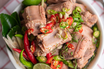 Boiled pork ribs in a white cup on a piece of fabric on a wooden table.