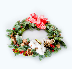 Fototapeta na wymiar Christmas wreath with red shiny beads with flowers of cotton and slices of dried oranges