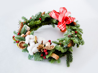 Fototapeta na wymiar Christmas wreath with red shiny beads with flowers of cotton and slices of dried oranges