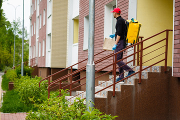 Young courier with thermo bag near the house. Food delivery service