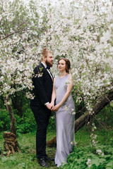 young beautiful couple in the garden against the background of cherry blossoms