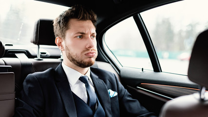 Stressed young businessman sitting in luxury car