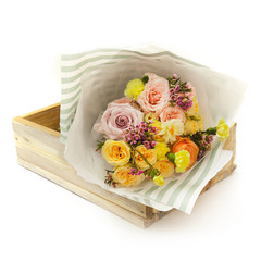 pink and yellow roses in wooden box, isolated on white background