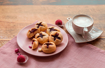 Cookies with raspberry filling, coffee with milk and pink chocolate candies